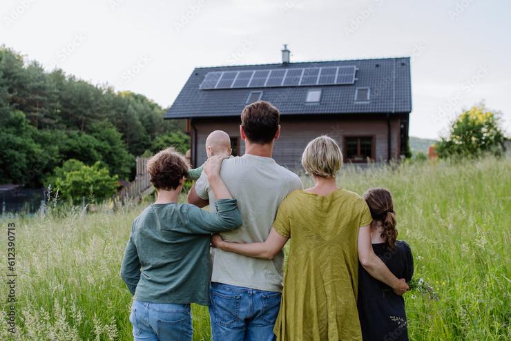 Rückansicht einer Familie, die sich ihr Haus anschaut.