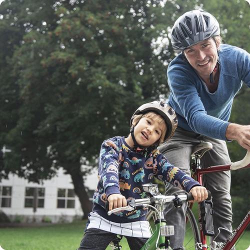 Kind und Vater fahren Fahrrad und lächeln in die Kamera